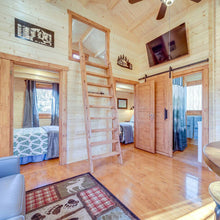 Load image into Gallery viewer, Wooden interior of a cabin with a ladder leading to a loft bed.