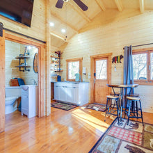 Load image into Gallery viewer, Wooden interior of a cabin with kitchen, dining area, and bathroom.