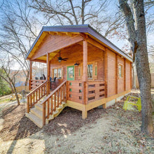 Load image into Gallery viewer, Wooden cabin with a deck surrounded by trees by WholeWoodCabins