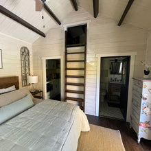 Load image into Gallery viewer, Cabin bedroom with wooden ladder leading to loft area, door to bathroom and door to kitchen
