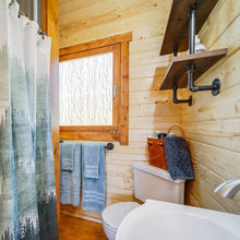 Load image into Gallery viewer, Bathroom with wooden walls, a toilet, sink, and shower curtain.
