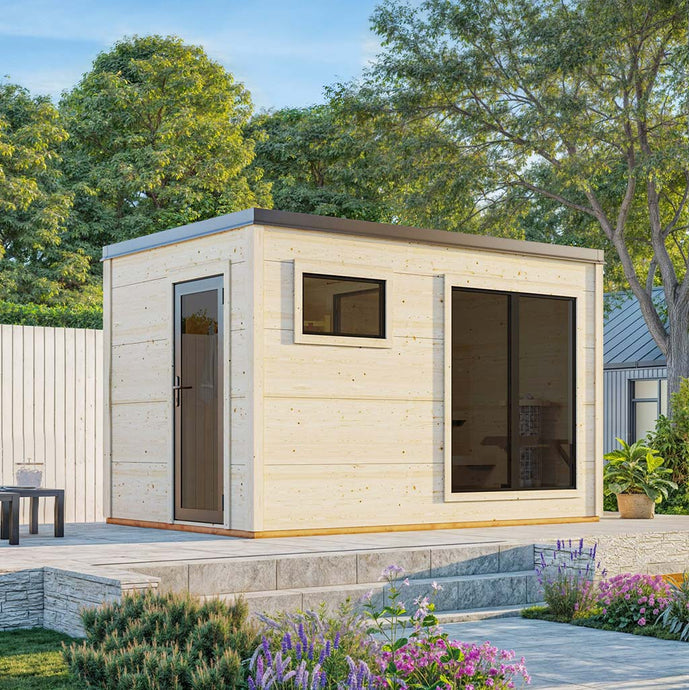 Modern light wood outdoor sauna with a flat roof, dark-framed windows, and a glass door, set on a stone patio with garden plants.